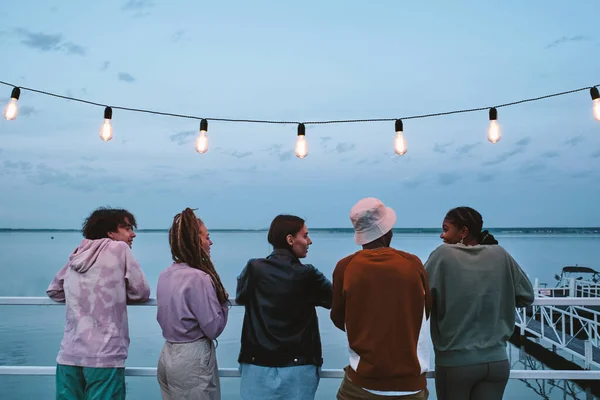 Groep van jonge vrienden op zoek naar Afrikaans meisje tijdens gesprek — Stockfoto