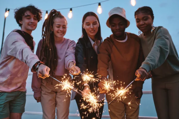 Group of young friends holding sparkling bengal lights — Stock Photo, Image