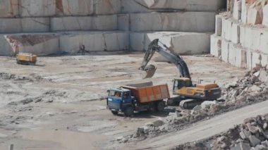 Kazıcının el bilgisayarı ağır ağır ağır taş ocağındaki kamyona granit blokları yüklüyor