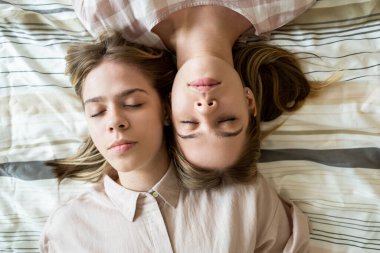 Yorgun genç ikiz kızlar uyurken yüzlerine dokunuyor.
