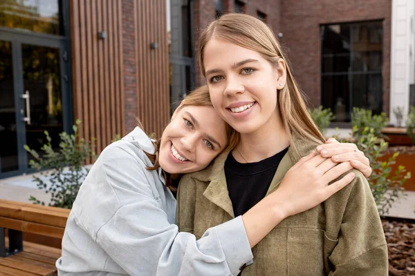 Zärtliche Zwillingsmädchen in T-Shirts und Jacken blicken in die Kamera — Stockfoto