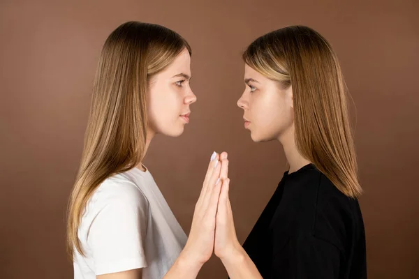 Side view of twin teenage girls touching by hands — Stock Photo, Image