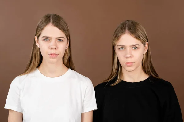 Две симпатичные серьезные девушки в футболках смотрят в камеру — стоковое фото