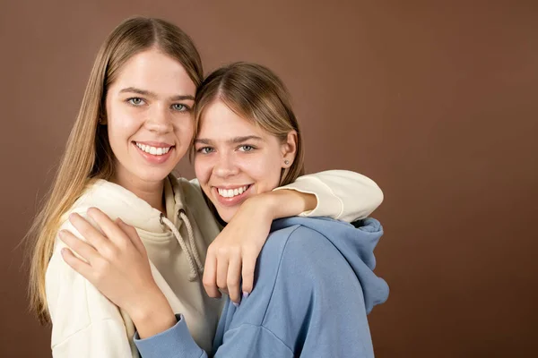 Two joyful teenage girls standing in embrace and looking at you — Stock Photo, Image