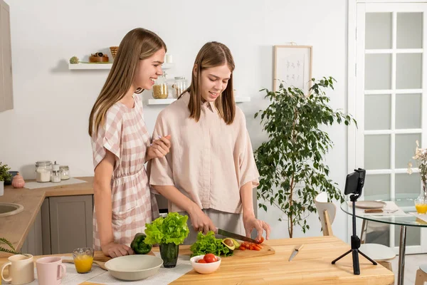 Dvě dospívající dívky vaření zeleninový salát během livestream — Stock fotografie