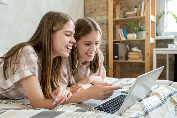 stock image Two cheerful teenage girls discussing moment of online movie