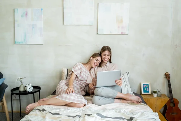 Zwei glückliche und liebevolle Teenager-Mädchen sehen Online-Film im Bett — Stockfoto