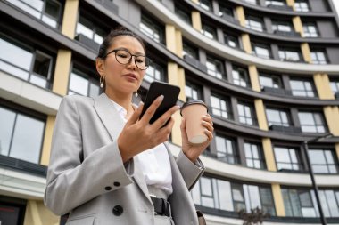 Zarif takım elbiseli çağdaş ajan akıllı telefon ekranına bakıyor.