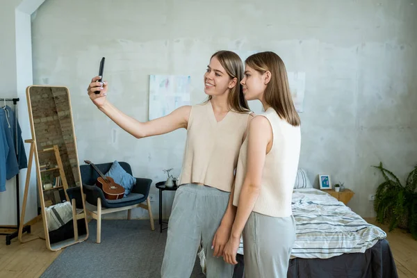 Dos chicas adolescentes felices mirando la cámara del teléfono inteligente mientras hacen selfie — Foto de Stock