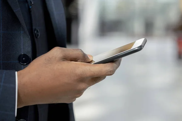 Рука молодого африканського комерсанта прокручується по мобільному телефону — стокове фото