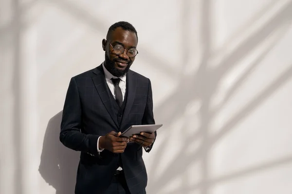 Šťastný mladý africký manažer v obleku rolování v tabletu — Stock fotografie