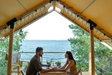 Genç romantik çift deniz kenarında yemek yiyor.