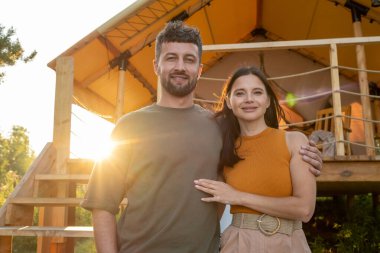 Mutlu genç bir adam, karısına sarılıyor.