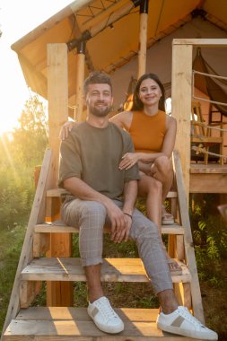 Sıradan giyimli mutlu çift tahta merdivenlerde dinleniyor.