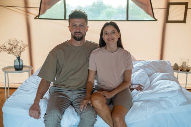 Genç adam ve kadın sabah yatağında oturuyor.