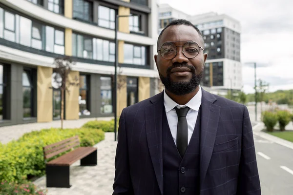 Fiatal afrikai üzletember öltönyben és szemüvegben városi környezetben — Stock Fotó