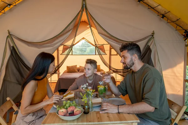 Feliz jovem família tomando café da manhã por glamping tenda — Fotografia de Stock