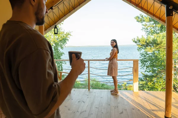 Mladá žena dívá na svého manžela s šálkem čaje — Stock fotografie