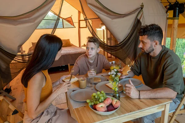 Dreiköpfige Familie interagiert beim Frühstück am servierten Tisch — Stockfoto