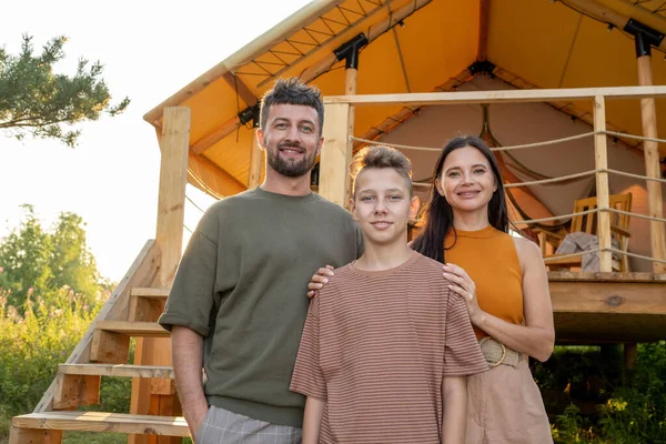 快乐的父母和他们十几岁的儿子站在摇摇欲坠的房子旁边 — 图库照片