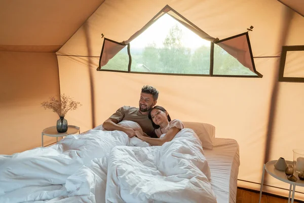 Couple affectueux assis dans le lit sous des draps blancs — Photo