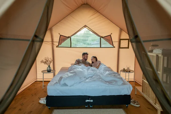 Amorous couple relaxing on large double bed in glamping house — Stock Photo, Image