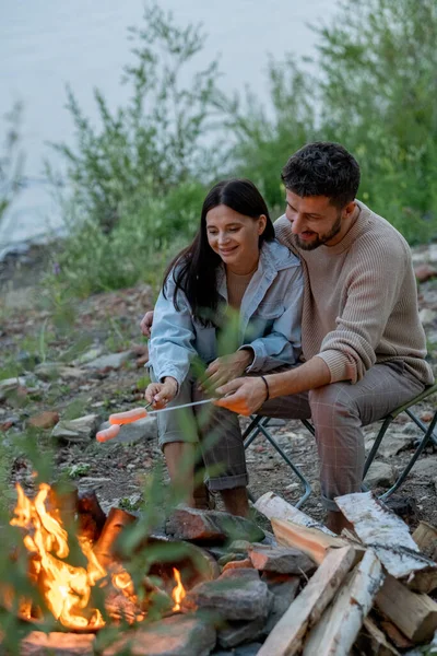 Mutlu genç çift kamp ateşinin yanında vakit geçiriyor. — Stok fotoğraf