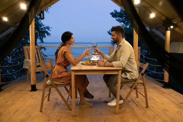 Mutlu genç karı koca kadeh tokuşturuyor şarap kadehleriyle