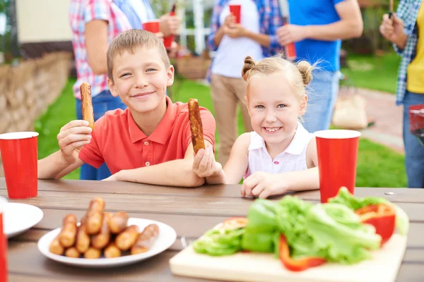 Dzieci jedzenia kiełbasy z grilla — Zdjęcie stockowe