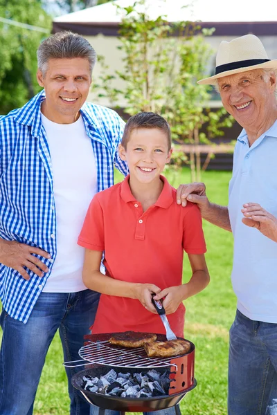 Grandpa, father and boy grilling sausages — Stock Photo, Image