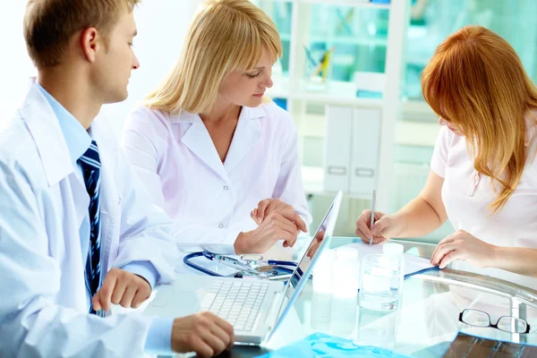 Twee beoefenaars kijken naar vrouwelijke patiënt — Stockfoto