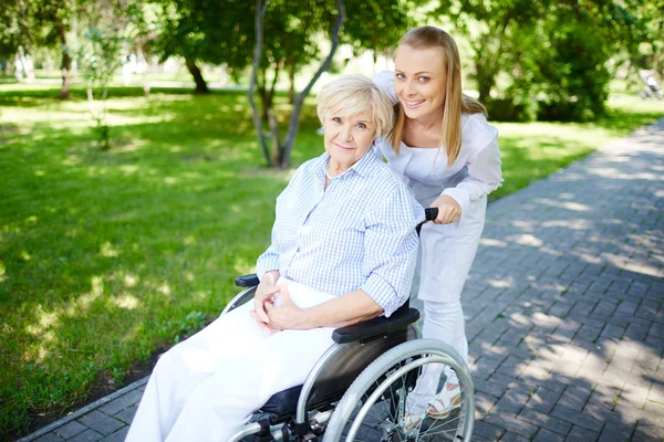 Femme soignante marchant avec une patiente âgée — Photo