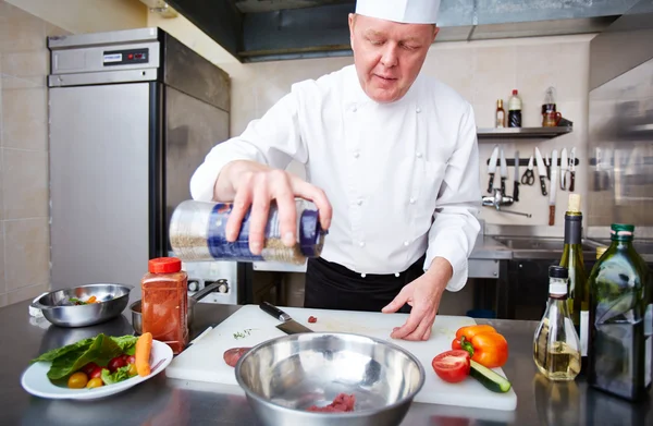 Chef masculino añadiendo especias a la carne — Foto de Stock