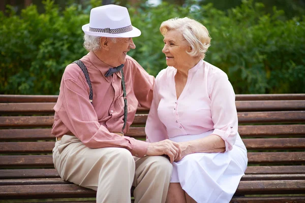 Äldre par talar på bänk — Stockfoto