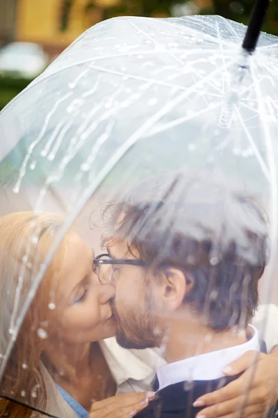 Liebespaar küsst sich unter Regenschirm — Stockfoto