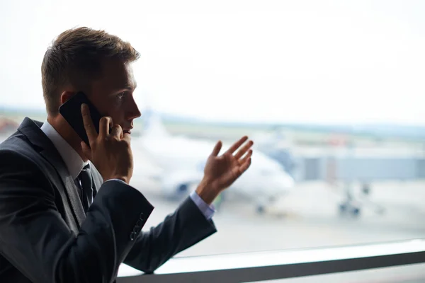 Businessman speaking on phone in airport — Stock Photo, Image