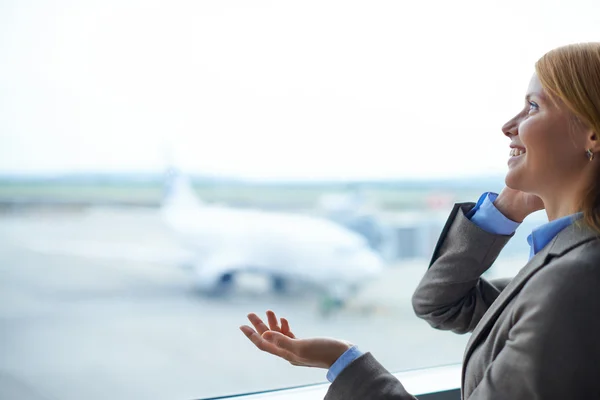 Businesswoman speaking on phone in airport — Stock Photo, Image