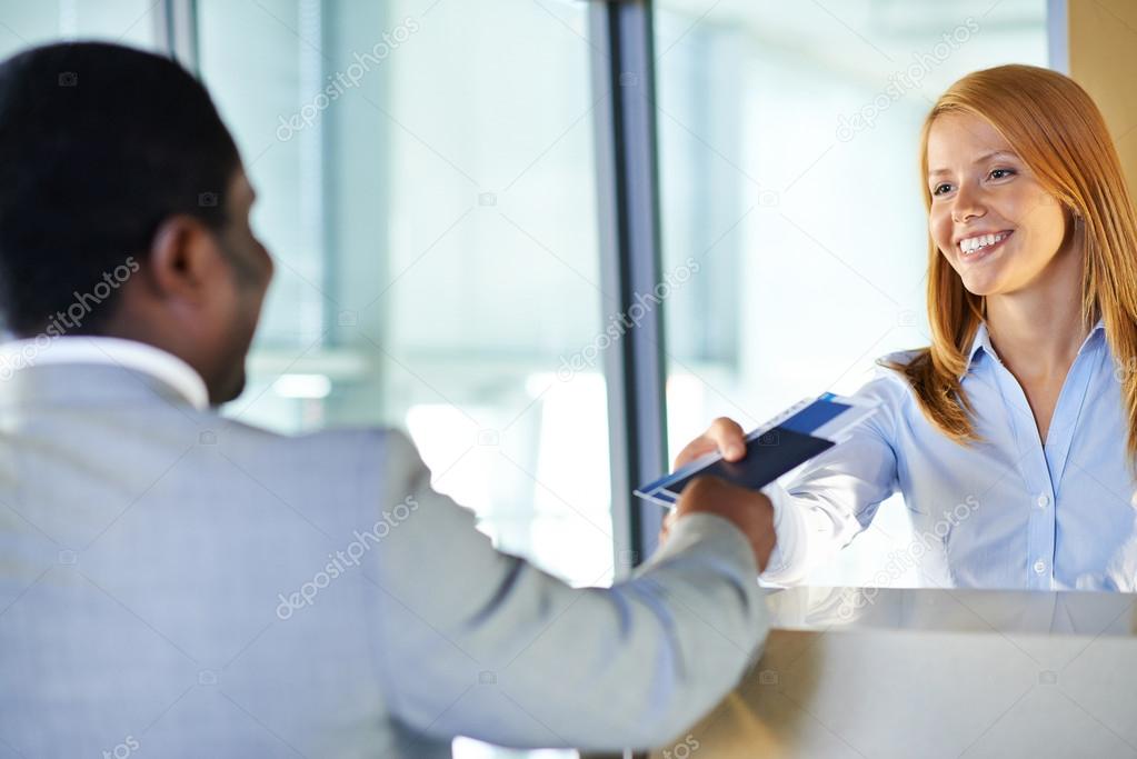 Woman giving passport and ticket to businessman at airport