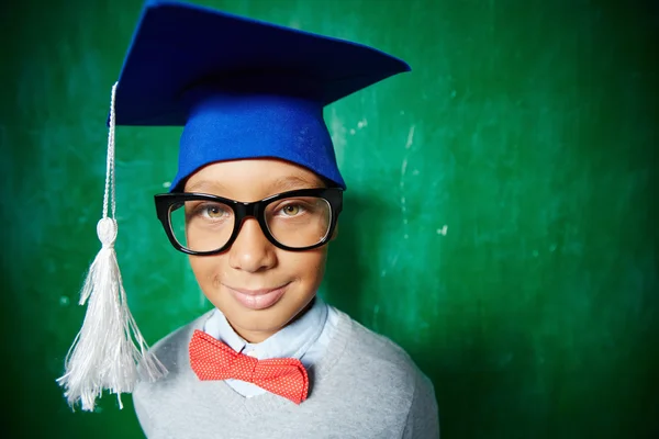 Elementary learner in eyeglasses and graduation hat — Stock Photo, Image