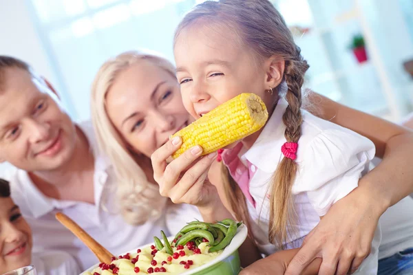 Girl eating corn from her mother hand — Stock Photo, Image