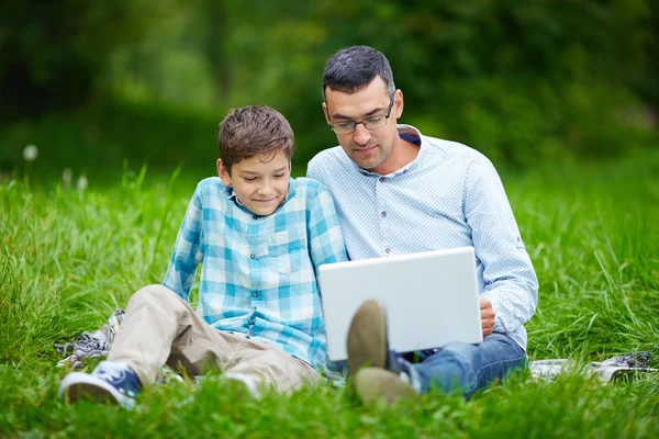 Padre e figlio utilizzando il computer portatile nel parco — Foto Stock