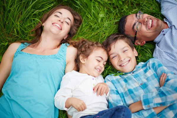 Семья лежит на зеленой траве — стоковое фото