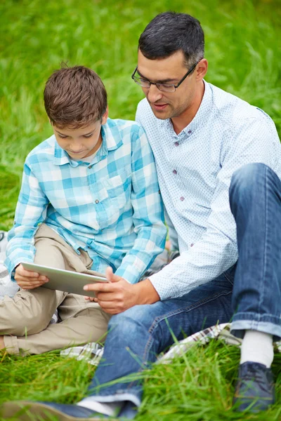 Pai e filho usando tablet digital ao ar livre — Fotografia de Stock