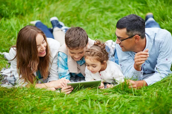 タッチパッドと草の上に横たわる家族 — ストック写真