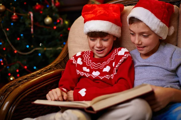 Děti v Santa čepice čtení knihy — Stock fotografie