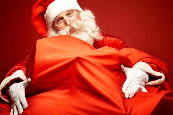 Santa Claus omhelst zak met presenteert — Stockfoto