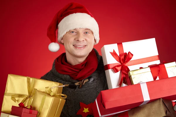 Hombre en Santa gorra sosteniendo regalos — Foto de Stock