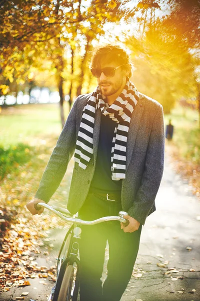 Uomo con bicicletta nel parco autunnale — Foto Stock