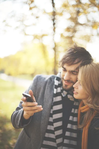 Couple lecture sms dans le parc d'automne — Photo