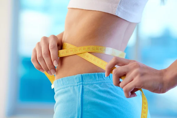 Mulher desportiva medindo sua cintura — Fotografia de Stock